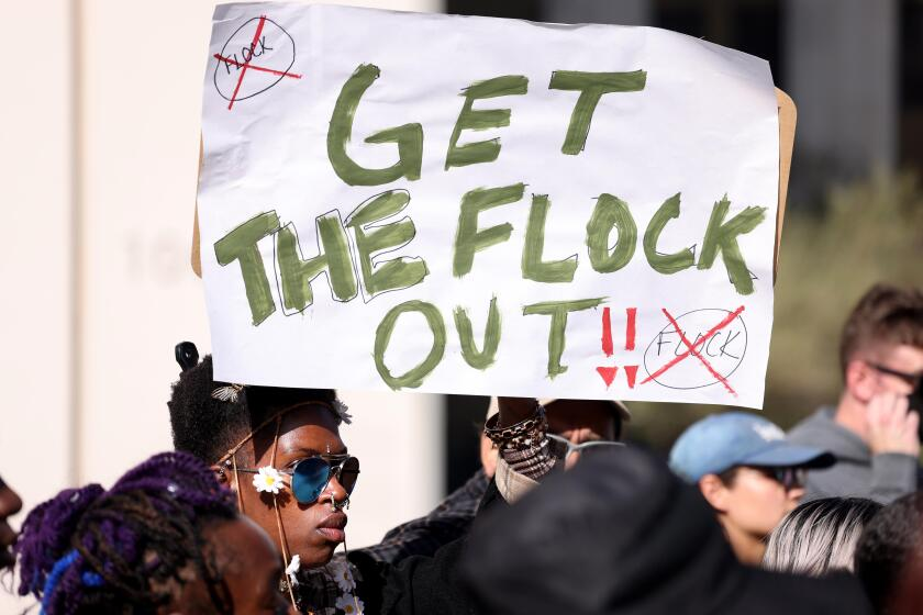 LOS ANGELES, CA - MARCH 3, 2026 - Queen AJ holds up a "GET THE FLOCK OUT," sign while joining members of the Stop LAPD Spying Coalition at a press briefing ahead of the Los Angeles Board of Police Commissioners meeting urging the department to end its partnership with Flock Safety in front of LAPD headquarters in downtown Los Angeles on March 3, 2026. Flock is an acronym for a technology company specializing in Automated License Plate Recognition (ALPR) cameras and software. They provide public safety, law enforcement, and neighborhood associations with devices that track vehicle license plates, make, color, and model, in real-time. The coalition and its partners have been calling for the dismantlement of this information sharing due to, what they allege, Flock ALPR data being used to facilitate mass deportations and criminalization. (Genaro Molina/Los Angeles Times)