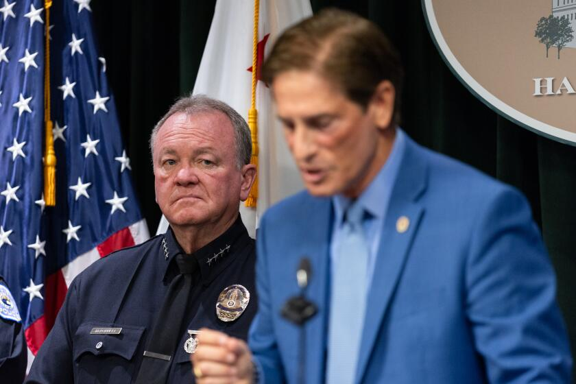 Los Angeles, California - August 06, 2026: Los Angeles Police Chief Jim McDonnell watches Los Angeles County District Attorney Nathan J. Hochman speak at a press conference about hate crimes at the Hall of Justice on Thursday, Aug. 6, 2026, in Los Angeles, California. Hate crimes in Los Angeles are going down in comparison to 2025. (Arwen Clemans/Los Angeles Times)
